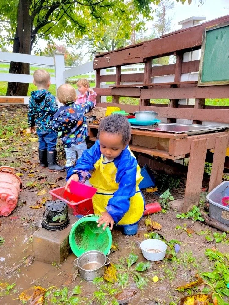 Children in rain gear playing at the outdoor mud kitchen