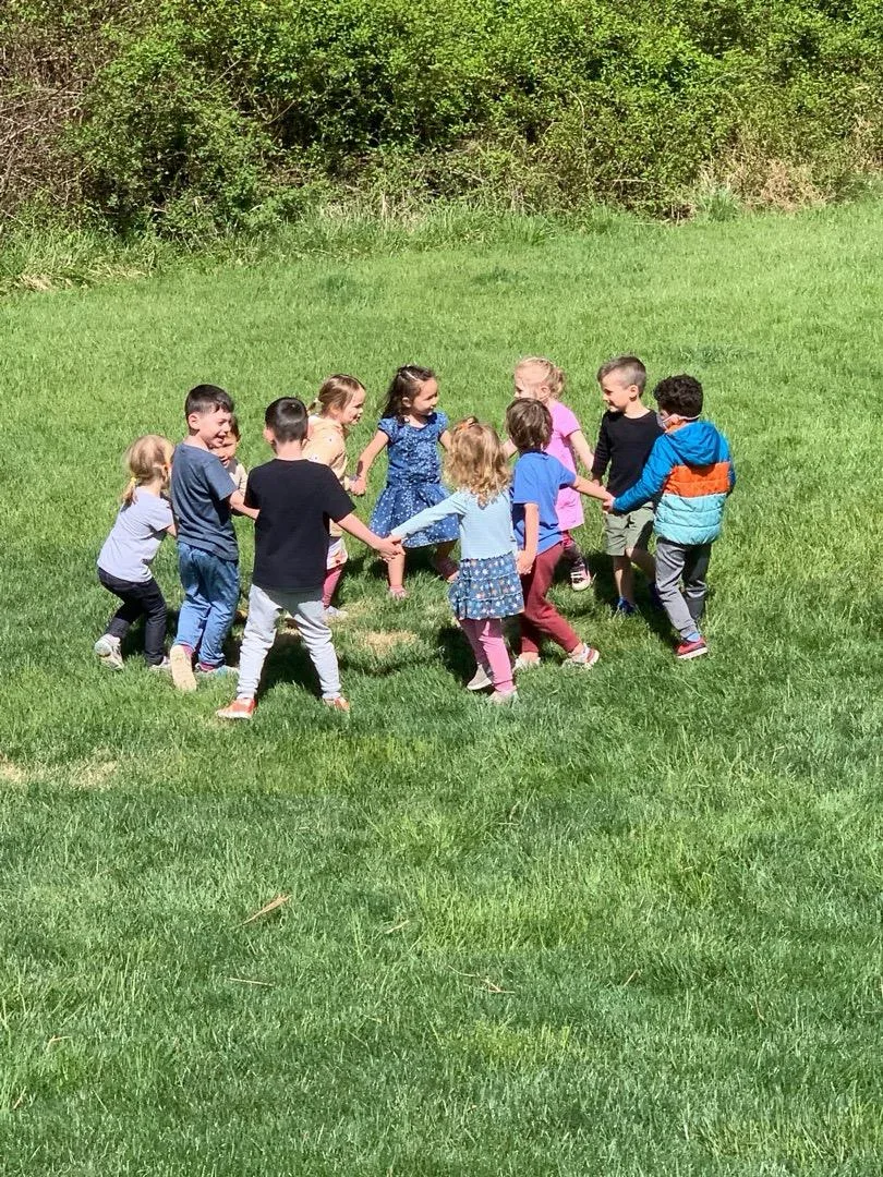 Children holding hands in a circle on the lawn