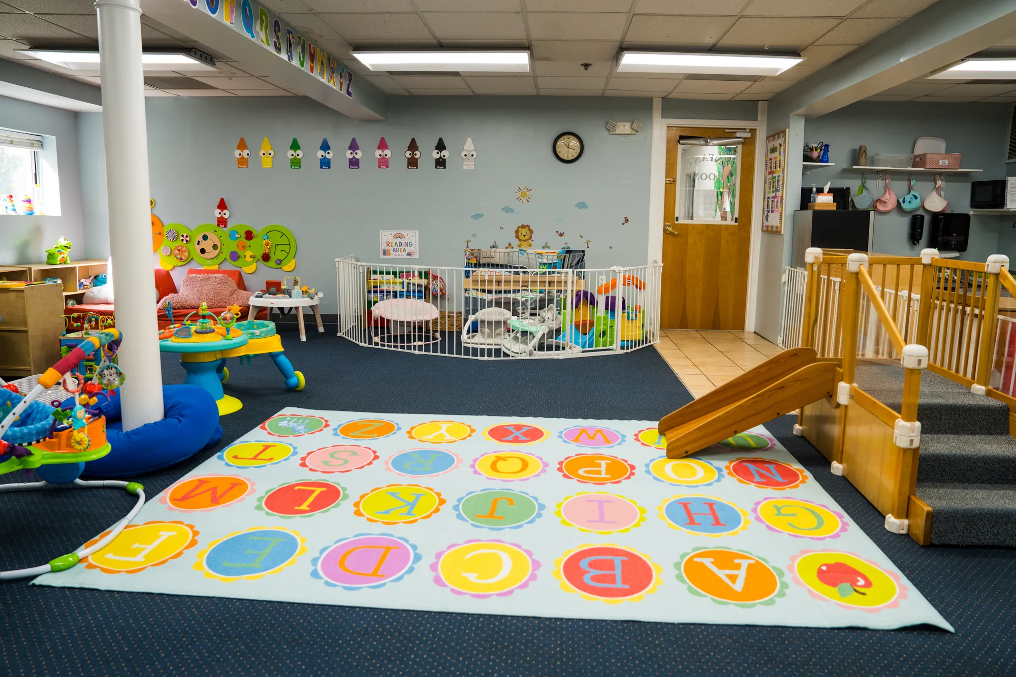 Infant play area with a wooden climber, slide, and alphabet mat