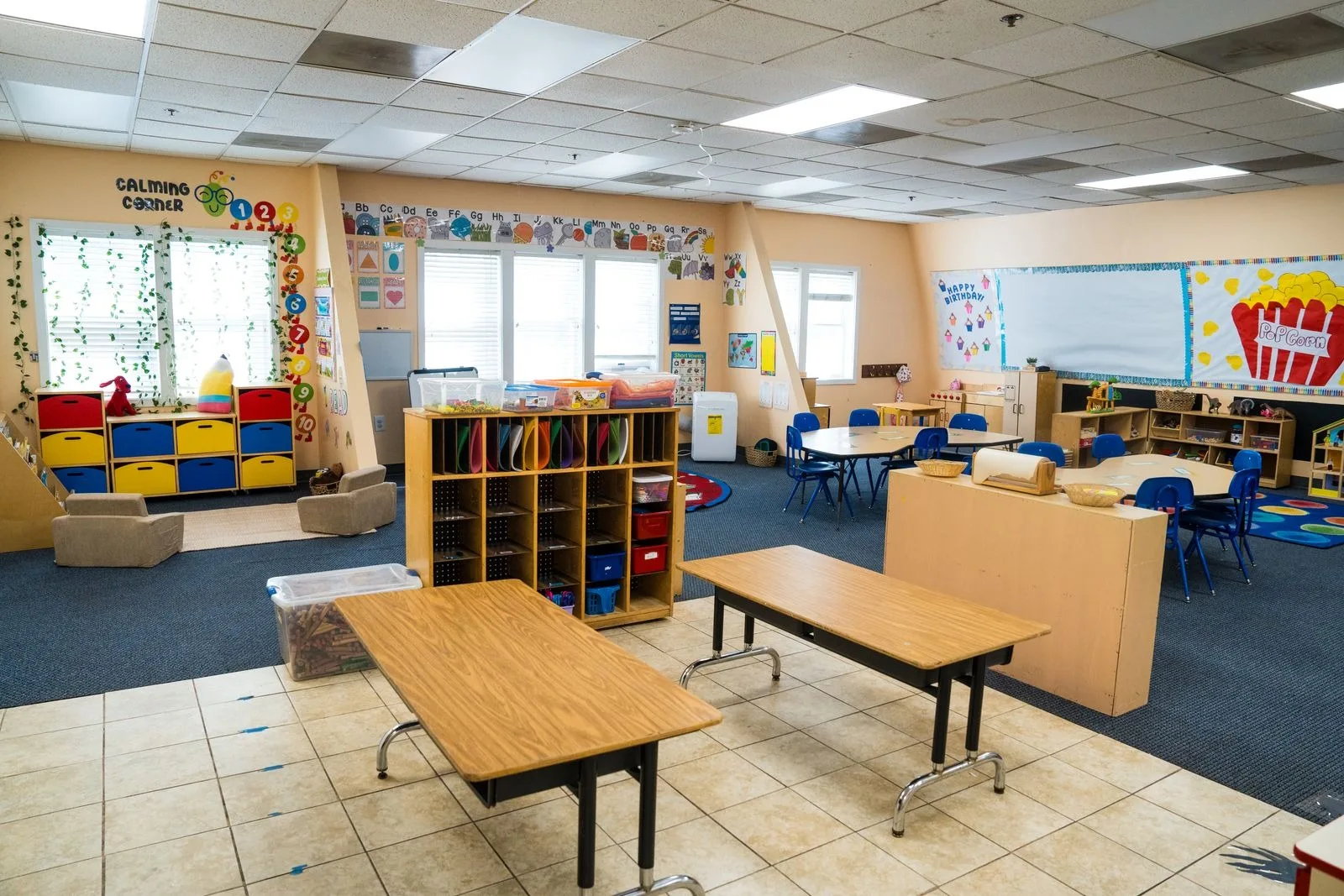 Pre-K classroom with learning centers, a doll house, and a colorful circle rug