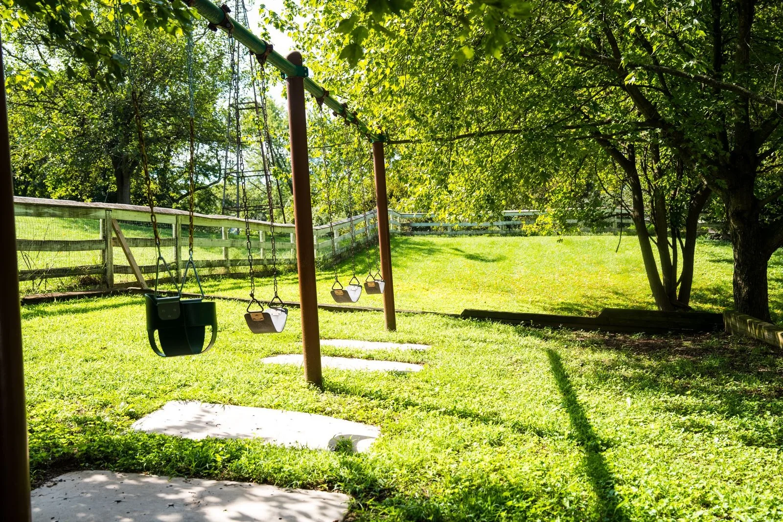 Swings on the shaded lawn behind the school
