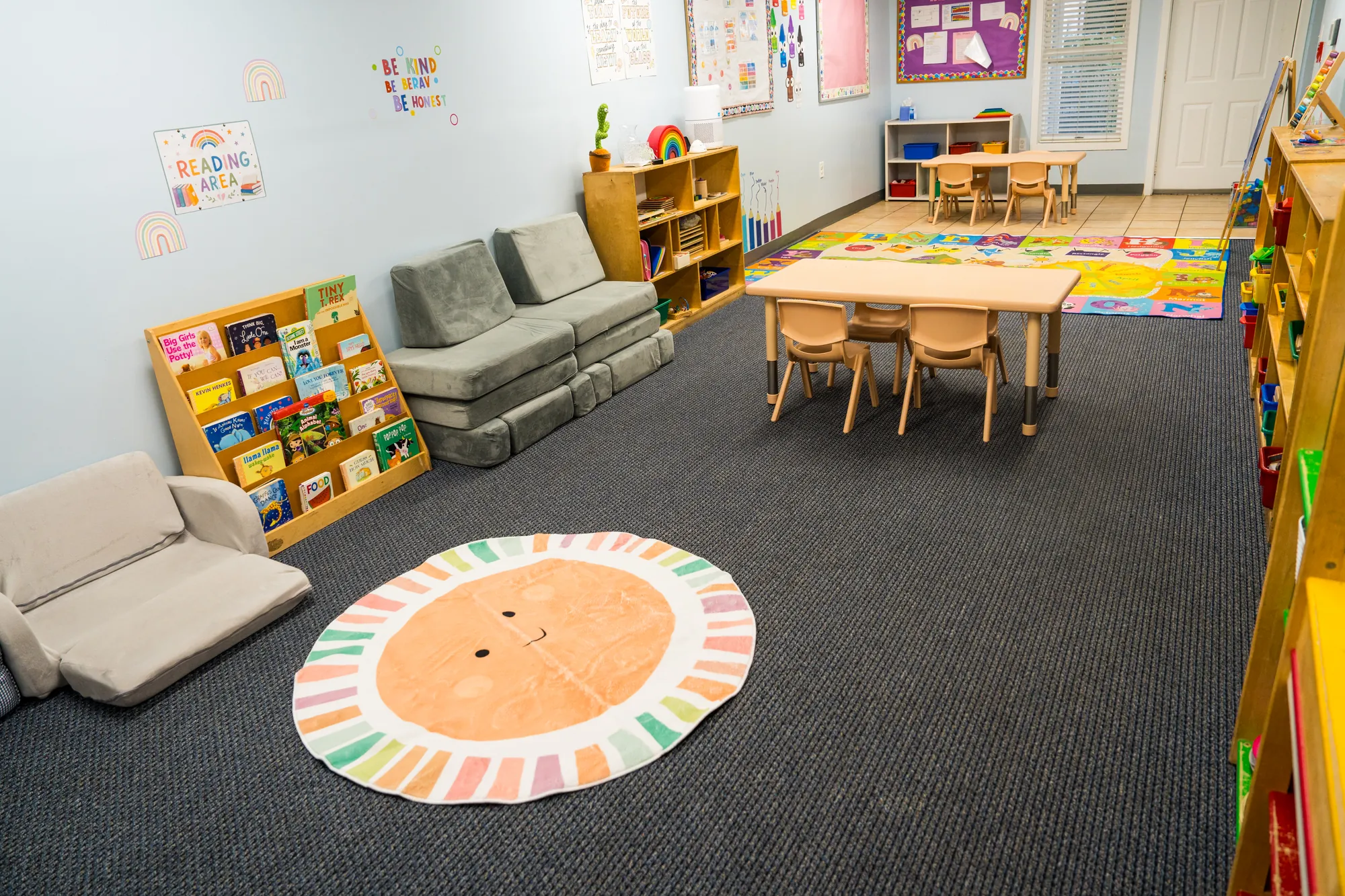 Second toddler room with a reading area, work tables, and open floor space