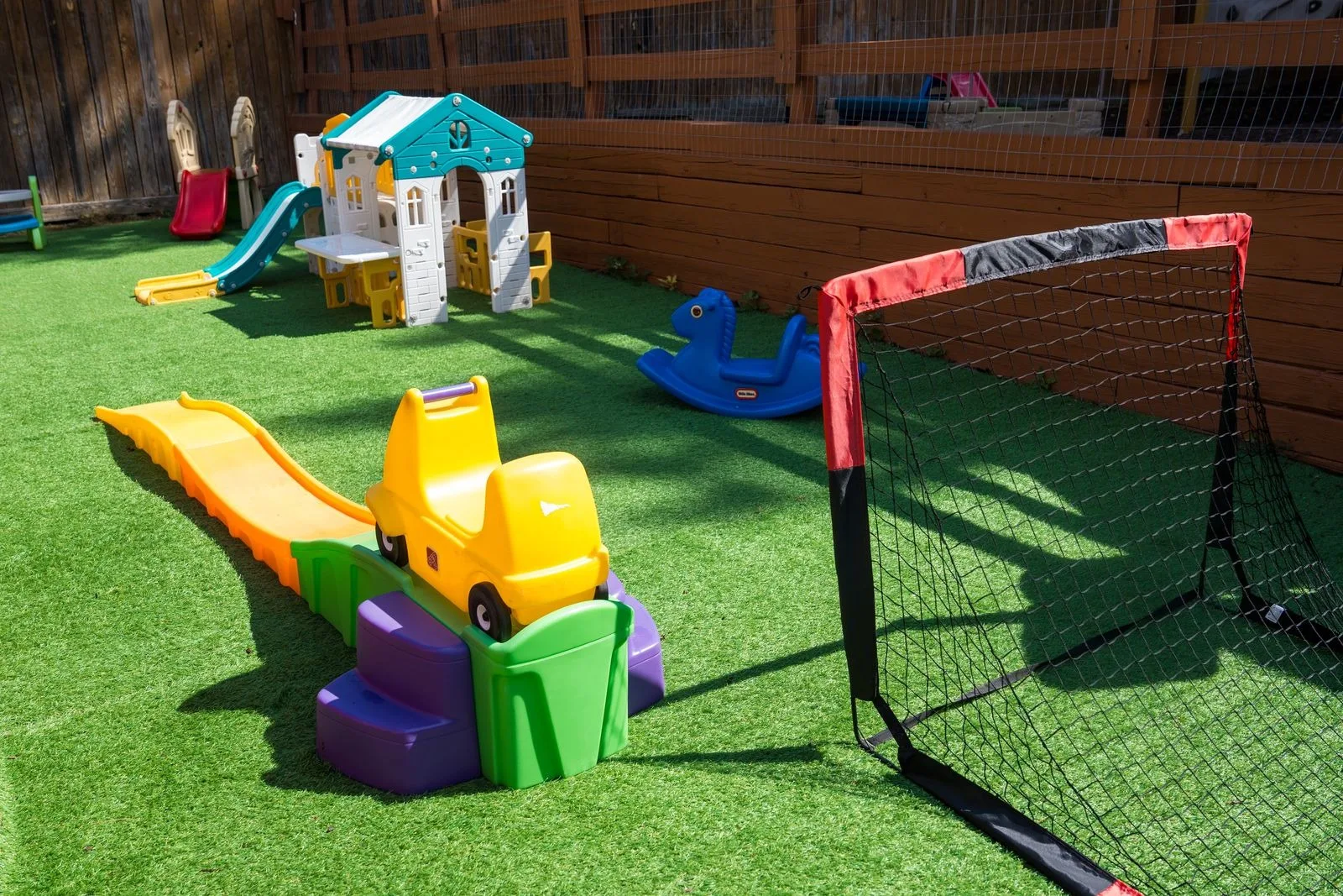 The turf play area with a playhouse, slide, rocker, and soccer goal